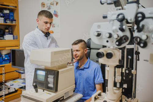 optometrist in an ophthalmologic clinic position head of patient for examination