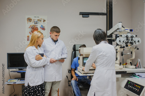 Eye Doctor/optometrist/ophthalmologist examining a young patient and explain to the students photo