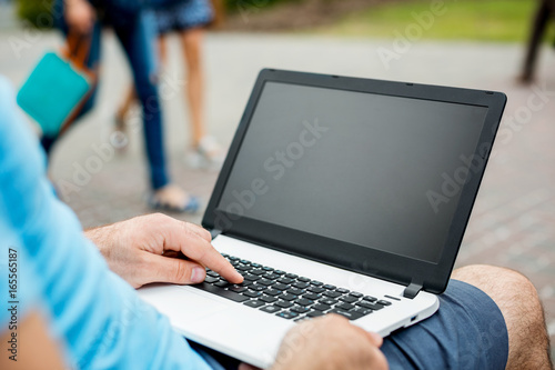 Close-up shot of handsome man's hands touching laptop computer's screen.