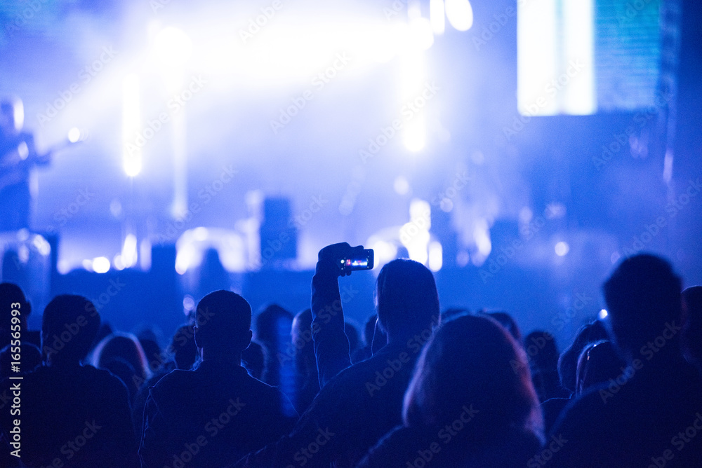 Raised arms holding smart phones to recording a live concert