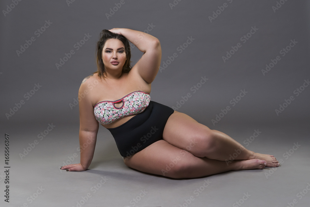 Plus size fashion model in sexy swimsuit, young fat woman on gray background, overweight female body Plus size fashion model in sexy swimsuit, young fat woman on gray background, overweight female body
