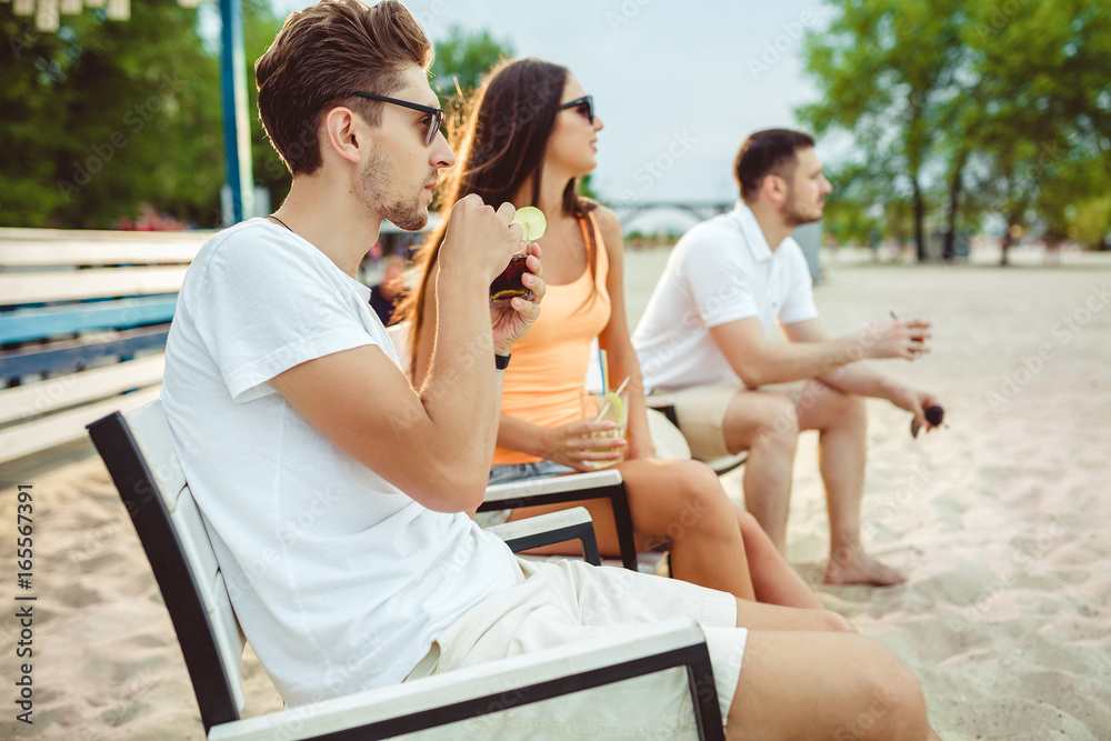 Young people enjoying summer vacation sunbathing drinking at beach bar