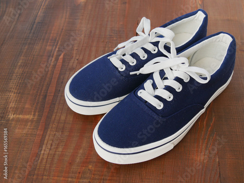 New unbranded blue denim sneakers on wooden background
