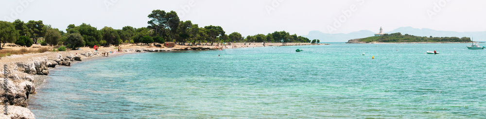 Panoramic view of Alcanada beach and island and lighthouse of the same name, on Majorca island, Spain