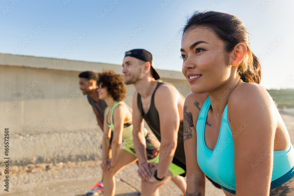 Young woman doing sports with a group of friends outdoors Young woman doing sports with a group of friends outdoors