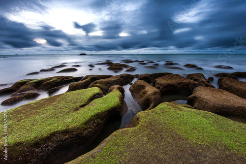 long exposure sunset seascape with green moss. Image contain soft focus due to long exposure.