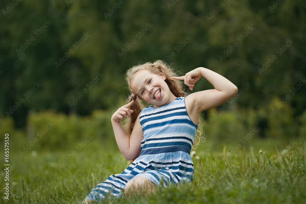 Pretty blonde smiling child wearing summer dress is playing in park Pretty blonde smiling child wearing summer dress is playing in park