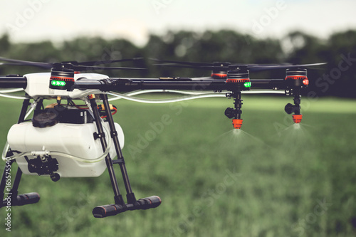 Closeup view of agriculture drone spraying water fertilizer on the green field. Drones spraying pesticides to grow potatoes.