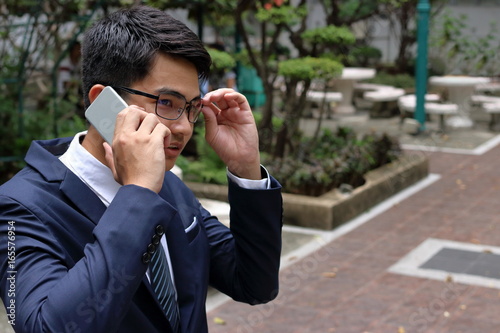 Handsome buinessman talking on his mobile phone in city park. photo