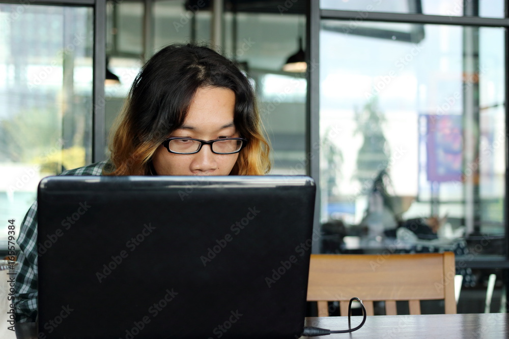 Fototapeta premium Close up young Asian worker looking his laptop in office against copy space background.