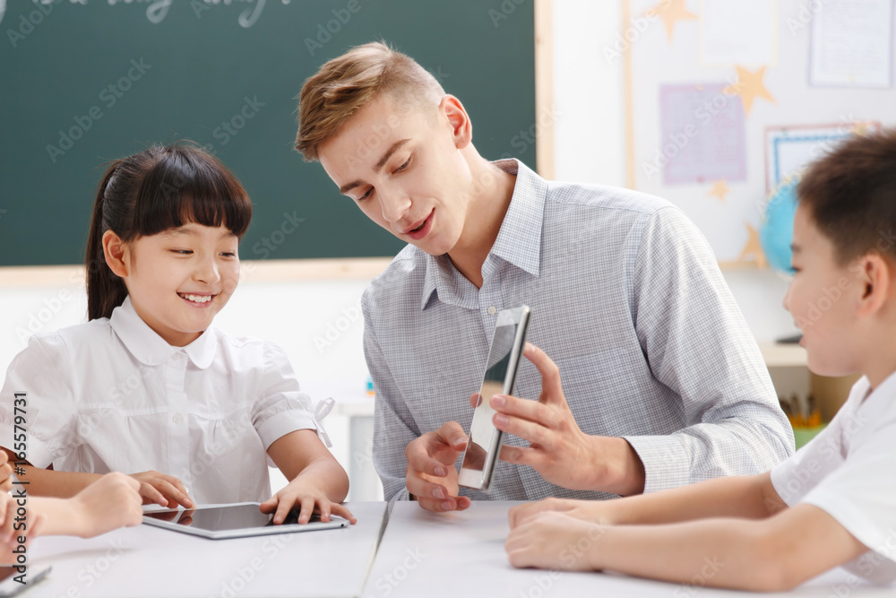 Male teacher helping students study in classroom Male teacher helping students study in classroom