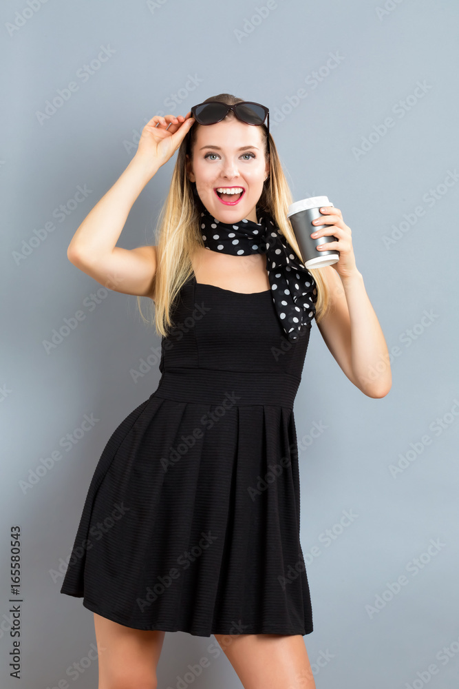 Happy young woman drinking coffee on a gray background Happy young woman drinking coffee on a gray background
