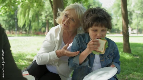 Hungry little boy eating sandwich while having a picnic