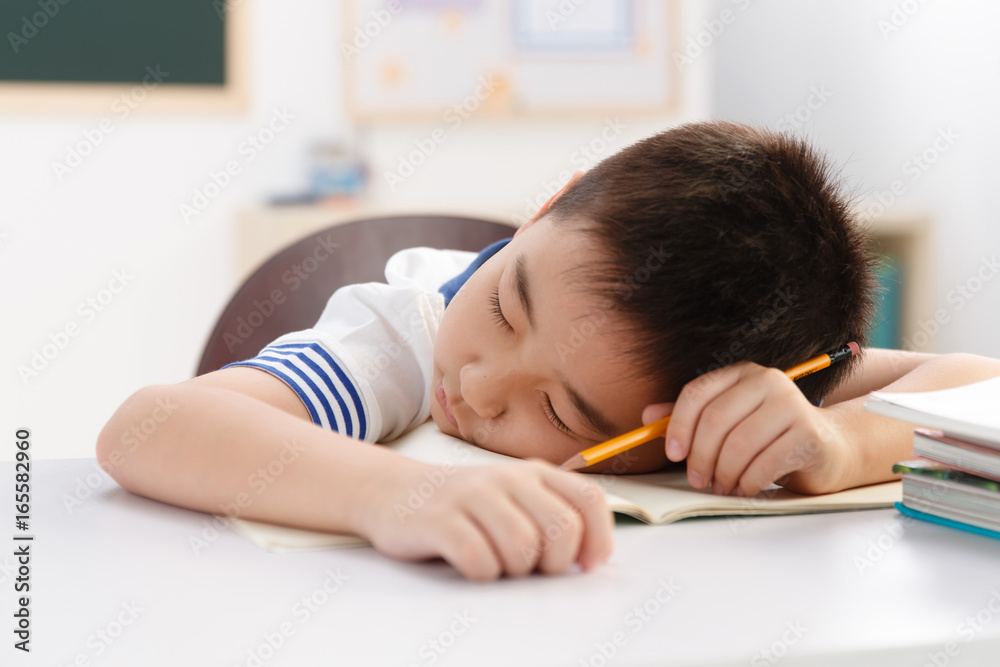 Tired school boy having rest in classroom Tired school boy having rest in classroom