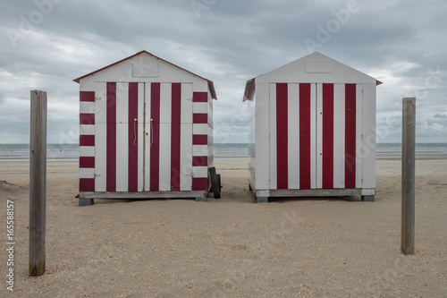 Two colorful beach cabins on a cloudy day in De Panne, Belgium.