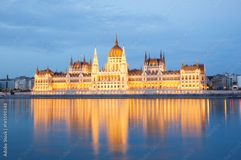 The building of Parliament with reflection in the river in Budapest at sunset