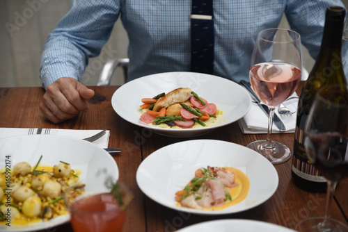 Wallpaper Mural Man sitting at table with assorted cooked dishes and wine  Torontodigital.ca