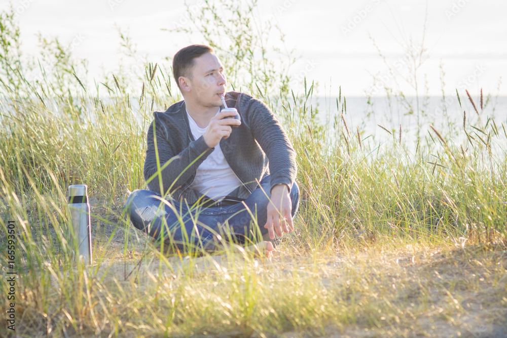 Young man drinking yerba mate on the Baltic sea coast Young man drinking yerba mate on the Baltic sea coast
