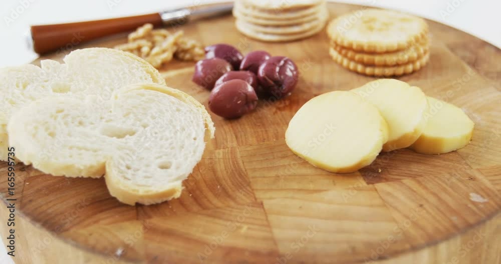 Slices of bread, crackers, olives, walnut and knife on wooden board Slices of bread, crackers, olives, walnut and knife on wooden board