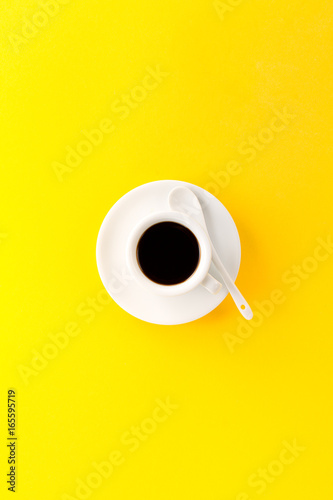 Coffee espresso in small white ceramic cup on yellow vibrant background. Minimalism Food Morning Energy Concept.
