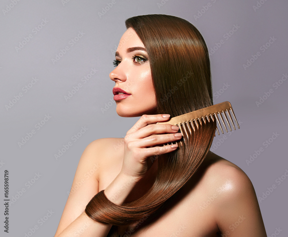 A beautiful young girl with long shiny silky hair sits and combs her hair with a A beautiful young girl with long shiny silky hair sits and combs her hair with a