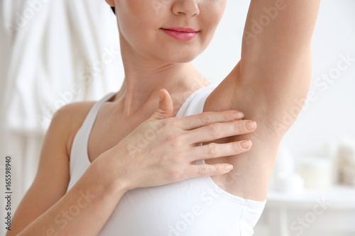 Closeup view of woman touching her armpit on blurred background. Epilation concept photo