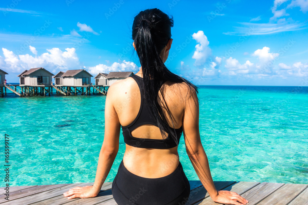 Obraz premium Portrait of happy young woman at beautiful water villa at Maldives island. Travel and Vacation. Outdoor shot.