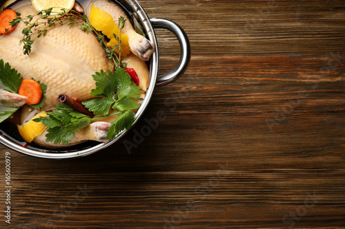 Cooking pot with turkey soaked in flavored brine on wooden table