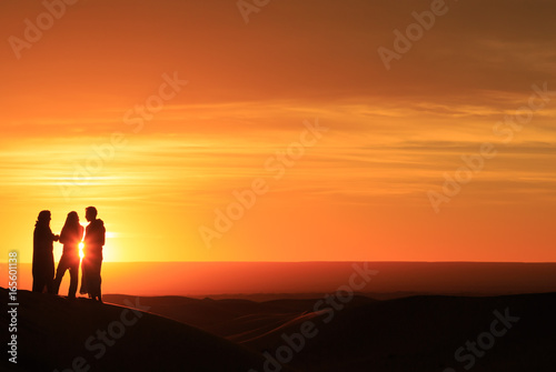 silhouette of men standing in the desert at sunset