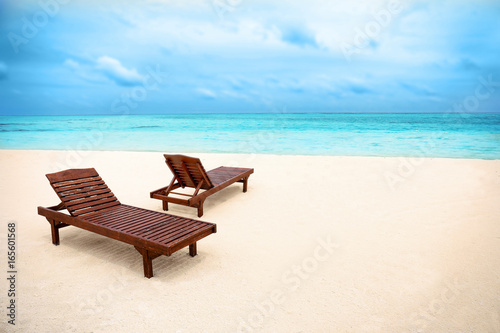 Sun loungers on beach in summer day