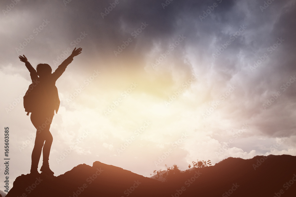 tourist girl stands on top of a mountain and has fun against backdrop of mountains and the river. setting sun. Concept to achieve the goal, go up, go to success