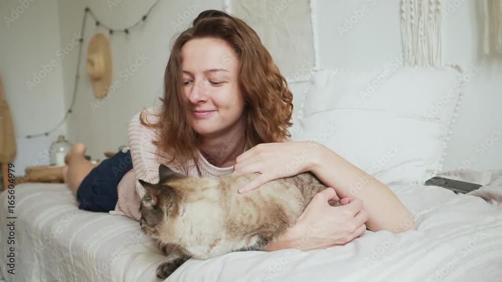 Woman at home lying and relaxing on the bed and cuddling a cat Woman at home lying and relaxing on the bed and cuddling a cat