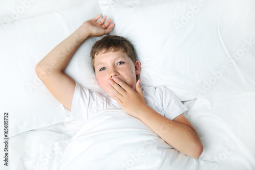 Young boy sleeping in white bed