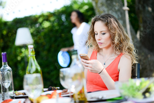 portrait of a beautiful young blond woman having lunch party with group of friends outdoor in summer