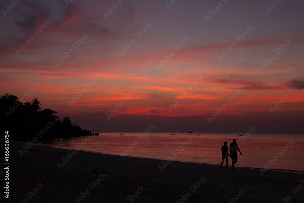 Tropical sunset beach with couple silhouette. High contrast