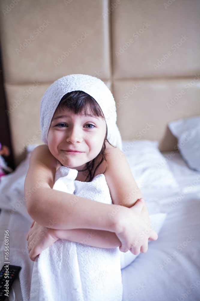 washed girl in a white towel sitting on a clean bed washed girl in a white towel sitting on a clean bed