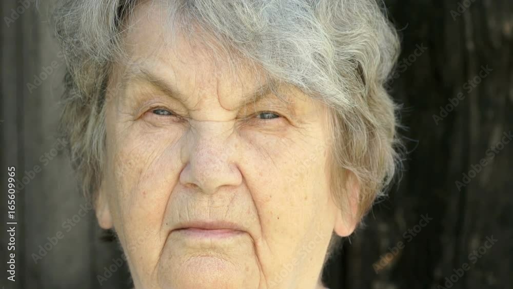 Portrait of serious mature old gramma aged 80s in outdoors in the background of wooden boards. Slow Motion Portrait of serious mature old gramma aged 80s in outdoors in the background of wooden boards. Slow Motion
