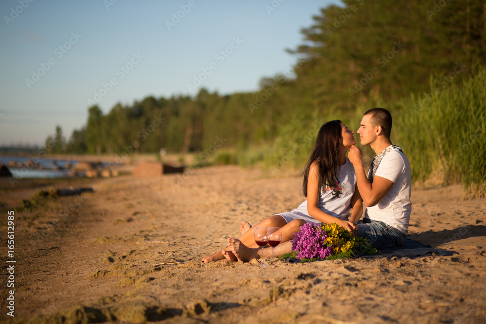 A young couple in love, on the shore of the Bay at sunset