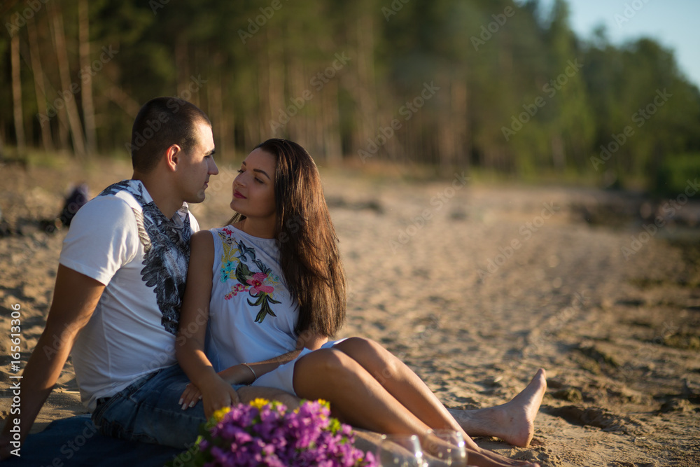 Naklejka premium A young couple in love, on the shore of the Bay at sunset