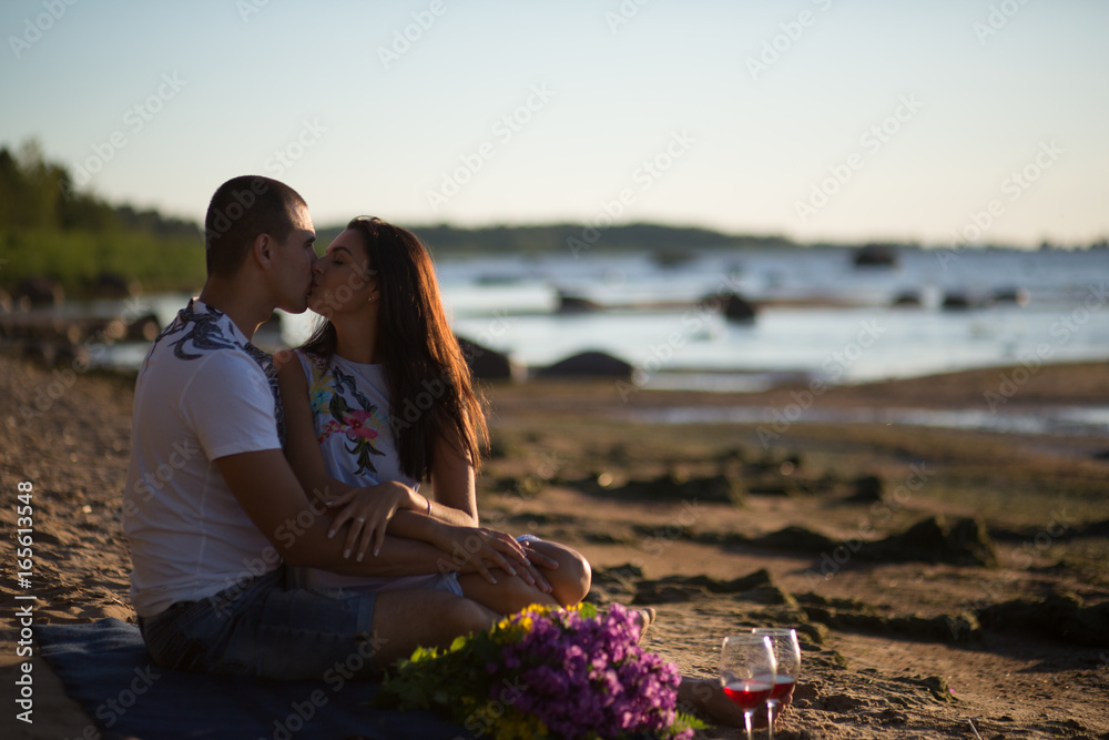 A young couple in love, on the shore of the Bay at sunset