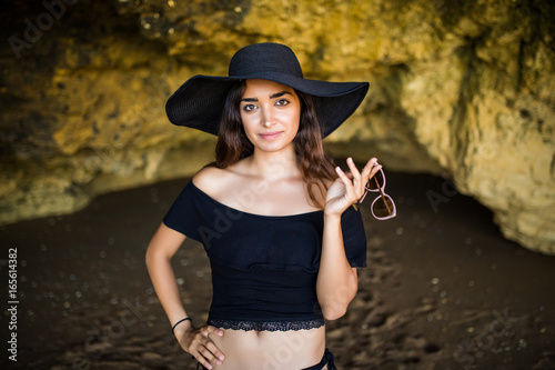 Happy Beautiful mexican woman with hat and sunglasses sunbathing on rocks beach on summer vocation time © F8  \ Suport Ukraine