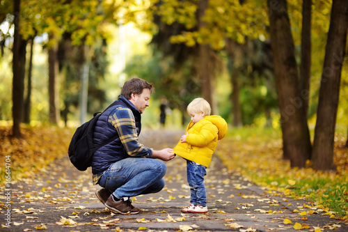 Father and his toddler son walking in autumn park