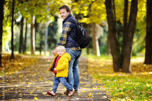 Father and his toddler son walking in autumn park