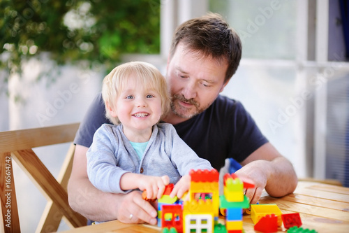 Obraz na plátně Little boy with his father playing with colorful plastic blocks at home