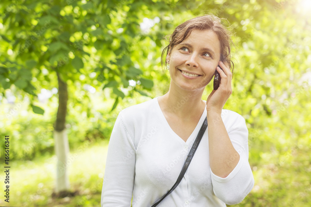Beauty young smiling girl is calling by phone in green park Beauty young smiling girl is calling by phone in green park