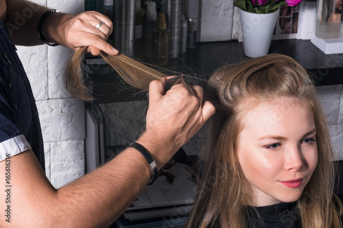 The hairdresser does a hairstyle to a young woman.