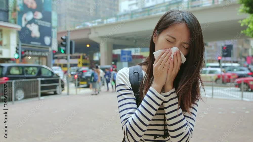 Woman sneezing at outdoor in Hong Kong city Woman sneezing at outdoor in Hong Kong city