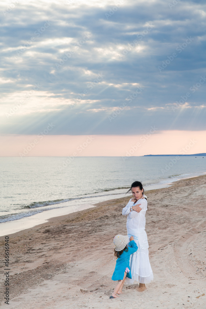 family mother and daughter on a sandy beach under a cloudy sky