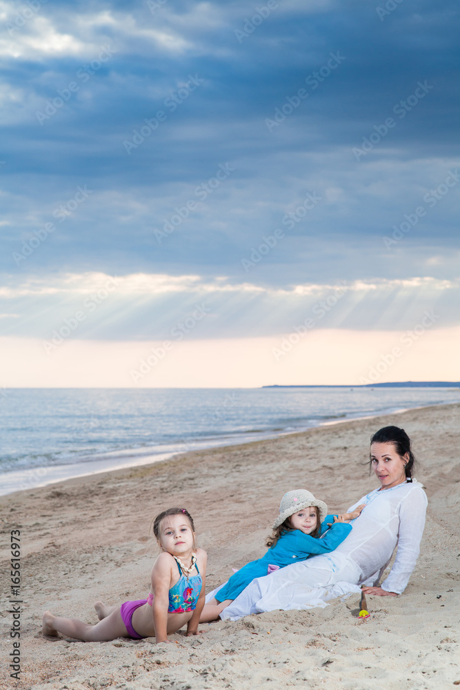 family mother and two daughters on a sandy beach under a cloudy sky