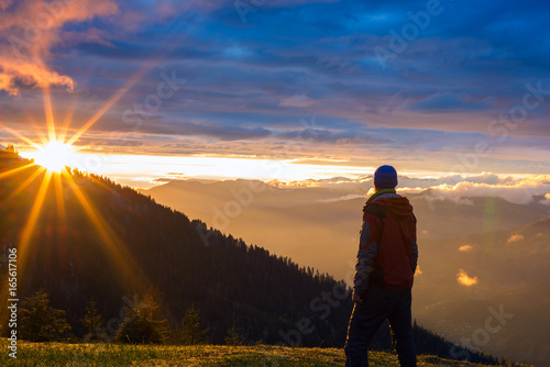 Lonely traveler stands in the mountains, during the sunset